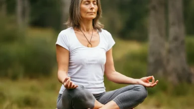 Person demonstrating proper breathwork posture, sitting on a cushion, natural setting